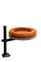 Side view of the Petyze cat desk bed featuring a plush bright-brown donut cushion on a gray circular base, mounted on a black adjustable metal arm and clamp designed to attach to a desk.
