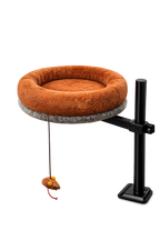 High-angle view of the Petyze cat desk bed featuring a plush burnt-brown donut cushion on a gray circular platform mounted to a black metal stand, with a hanging mouse toy attached underneath the bed.