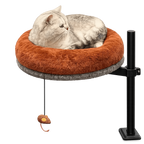 Light-colored tabby resting in the raised Petyze cat desk bed with plush brown cushion and hanging toy.